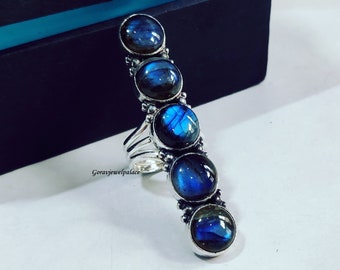 May include: A silver ring with five blue labradorite gemstones set in a row. The ring is a statement piece with a unique design.