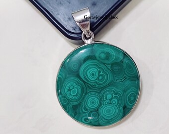May include: A round green malachite pendant with a silver bail. The malachite has a swirling pattern of green and black.