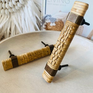 Könnte beinhalten: Zwei geflochtene Rattanknaufgriffe mit Messingakzenten. Die Griffe haben ein geflochtenes Design und sind mit Schrauben an einer Metallbasis befestigt.