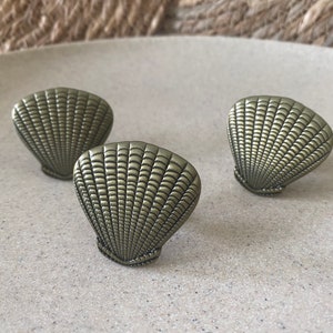 May include: Three gold-coloured metal seashell-shaped drawer pulls.