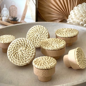 May include: Set of eight round woven rattan knobs with a natural wood base. The knobs are light brown in colour and have a woven pattern.