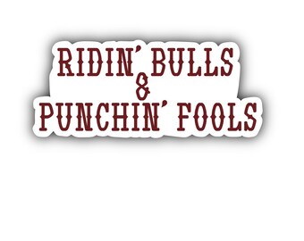 Op de afbeelding: Een witte sticker met bruine tekst die "RIDIN' BULLS & PUNCHIN' FOOLS" zegt.