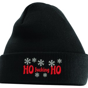 Könnte beinhalten: Schwarze Strickmütze mit einem roten gestickten Design, das "HO fucking HO" mit Schneeflocken auf beiden Seiten des Textes sagt.
