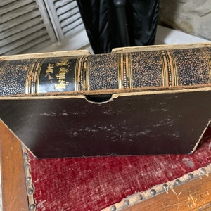 Può includere: Un libro vintage rilegato in pelle nera con dettagli dorati e il titolo "Der heilige Krieg" sul dorso.