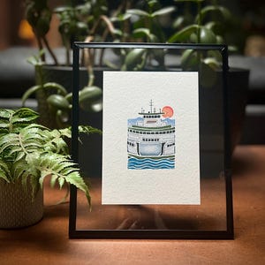 May include: Framed watercolor print of a ferry boat with a red sun in the background. The ferry is white, blue, and green, with blue water at the bottom. The black frame is rectangular.