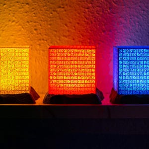 Poneglyphs iluminados con luz de diferentes colores, cada uno con inscripciones talladas, destacando sus detalles en una escena que recuerda los secretos de los Piratas del Sombrero de Paja
