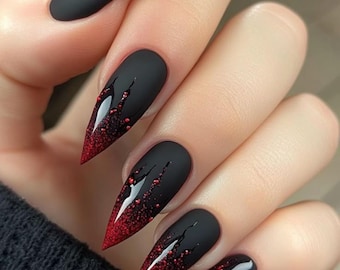 May include: Matte black stiletto nails with a red glitter ombre effect at the tips. The nails feature a dark red drip design with small red glitter accents, creating a dramatic and stylish look.