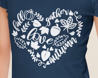 May include: A navy blue t-shirt with a white heart-shaped design featuring the words "fall", "gather", "love", and "autumn" surrounded by leaves, acorns, and hearts.