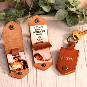 May include: Three brown leather keychains with metal snaps. One shows a couple, one displays the text 3 Years Down FOREVER to go A+M with a baby photo, and one is embossed with the name SMITH and attached to a gold-toned metal key ring.