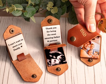 May include: Three brown leather keychains with metal snaps. One displays 'I can't wait to meet you Daddy', another shows an ultrasound image with 'Thank you for being the most amazing father & partner', and the third features a photo and 'DAD'.