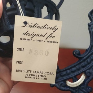 May include: A black metal lamp with a white porcelain socket and a tag that reads "Distinctively designed for Yesterday Today Tomorrow" and "Style #360". The tag also includes the company name "Brite-Lite Lamps Corp." and address "30 Prince Street Brooklyn N.Y. 11201".