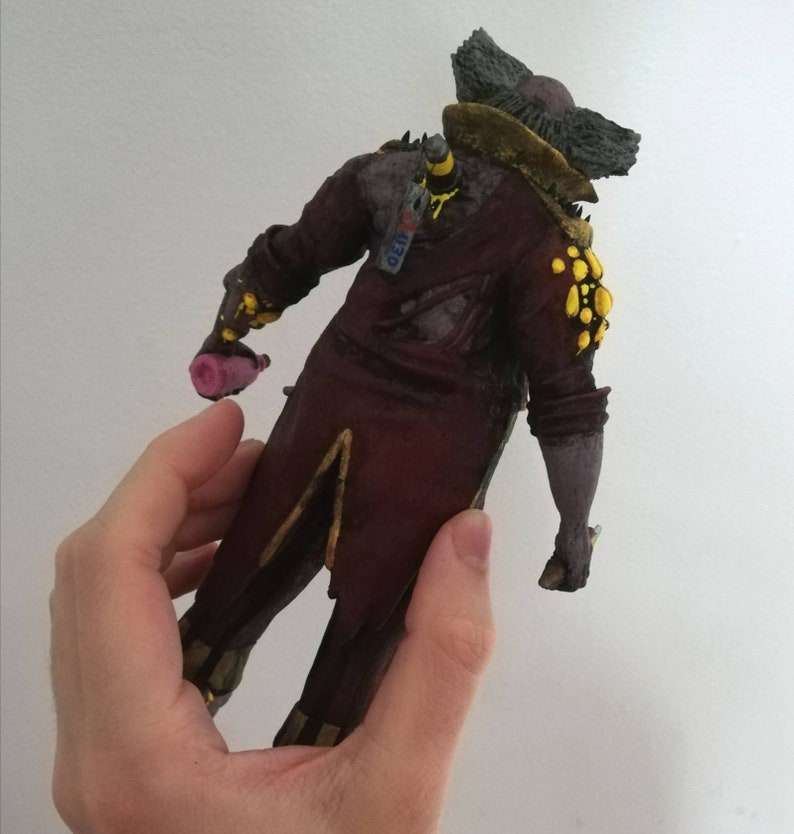 May include: A 3D printed figurine of a character wearing a red and gold costume with yellow accents. The character has a large, bushy beard and is holding a pink object in its hand. The figurine is standing on a white background.