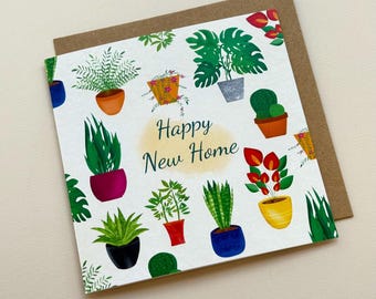 May include: A square greeting card with a white background featuring various potted houseplant illustrations in colorful pots. The text Happy New Home is printed in dark blue in the center. The card is placed on a brown paper envelope.