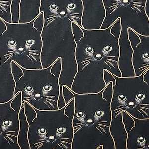 May include: A black and white fabric with a repeating pattern of black cats with gold outlines. The cats have green eyes and are looking directly at the viewer.