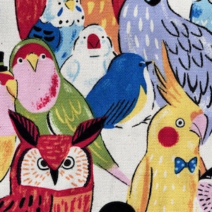 Könnte beinhalten: Ein farbenfroher Stoff mit Illustrationen verschiedener Vögel, darunter Eulen, Papageien und Sittiche. Die Vögel sind in leuchtenden Farben wie Rot, Blau, Gelb und Grün dargestellt, vor einem weißen Hintergrund. Das Design ist skurril und verspielt.