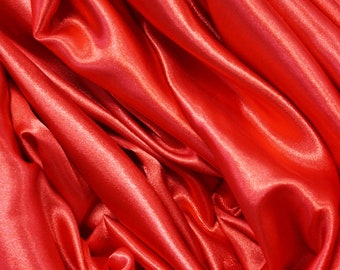 May include: Close-up of a smooth, red satin fabric with soft folds and wrinkles.