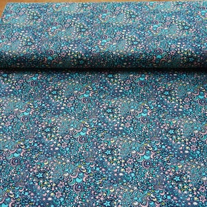 Puede incluir: Una tela azul oscuro con un patrón repetitivo de estrellas, lunas y remolinos en tonos de rosa, turquesa, amarillo y blanco.