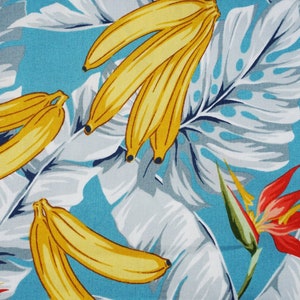Puede incluir: Una tela azul con un estampado tropical que presenta plátanos amarillos, hojas blancas y grises y una flor roja.
