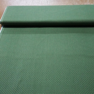 May include: A green fabric with a small white polka dot pattern. The fabric is folded in half and has a white edge.