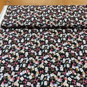 Puede incluir: Tela negra con un patrón blanco repetido de cartas de juego, tazas de té y personajes de Alicia en el País de las Maravillas.
