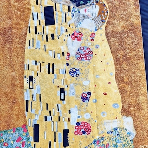 Könnte beinhalten: Ein Wandteppich mit Gustav Klimts "Der Kuss". Das Kunstwerk zeigt ein sich umarmendes Paar, dessen Figuren mit Gold, Schwarz und bunten Mustern verziert sind. Der Hintergrund ist ein strukturierter, goldbrauner Farbton mit einem Blumenmuster am unteren Rand.