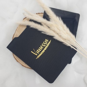 Könnte beinhalten: Schwarze personalisierte Tablethülle mit dem Namen "Vanessa" in goldenen Buchstaben und einem goldenen Lorbeerkranz-Design.