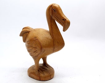 May include: A wooden carving of a dodo bird, a flightless bird native to Mauritius. The carving is brown and has a detailed design.
