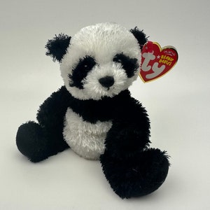 Może przedstawiać: Pluszowy miś panda w kolorze czarno-białym siedzący na białym tle. Panda ma czarny nos i czarne oczy. Panda nosi czerwoną metkę z napisem "Original Beanie Babies Ty".