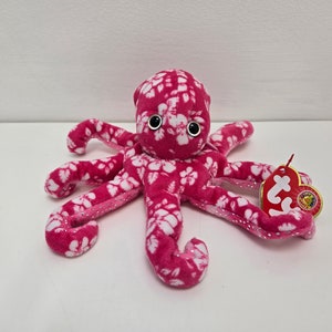 May include: Pink plush octopus with white floral print and black eyes. The octopus has eight tentacles and a Ty tag attached to one of the tentacles.