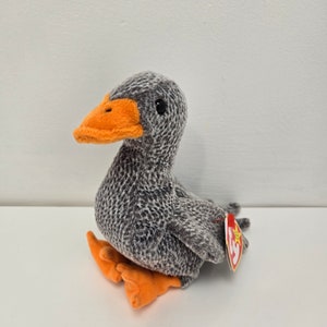 May include: Gray and orange plush goose toy with a red and white tag that says "Ty" and has a star on it.