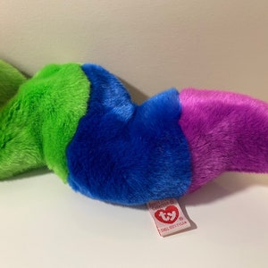 Op de afbeelding: Een veelkleurig pluche speelgoed in de vorm van een worm. De worm is oranje, groen, blauw en paars. Het speelgoed heeft een Ty-label eraan bevestigd met de tekst "Ty, Beanie Babies, Small  (6"  tall)".
