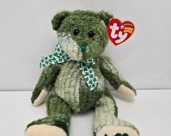 Peut inclure: Ours en peluche vert et blanc avec un trèfle vert sur son pied. L'ours porte un ruban vert avec des trèfles blancs. L'ours a une étiquette Ty Beanie Babies attachée à son oreille.