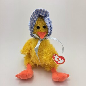 May include: Yellow plush chick toy wearing a blue and white gingham bonnet. The chick has a yellow beak and orange feet. The toy has a Ty tag attached to it.