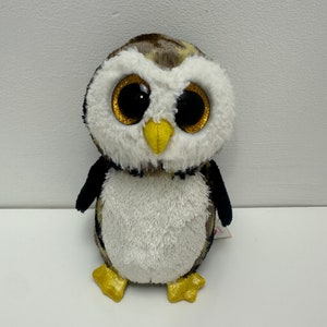 May include: A brown and white owl plush toy with large, glittery eyes. The owl has a yellow beak and feet.