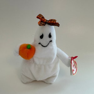 May include: White plush ghost holding a small orange pumpkin with a black and orange bow on its head. The ghost has a black smiling face and a Ty tag attached to its arm.