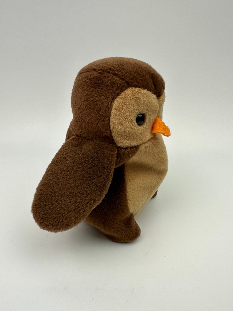 K&ouml;nnte beinhalten: Eine braune und beige Pl&uuml;sch-Eule mit einem kleinen orangefarbenen Schnabel. Die Eule sitzt auf einem wei&szlig;en Hintergrund.