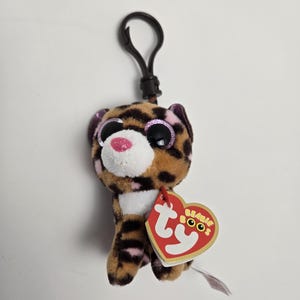 May include: A brown and white tiger plush keychain with pink glitter eyes and a Ty Beanie Boos tag.
