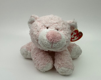 Può includere: Un peluche a forma di gatto rosa con muso e zampe bianche. Il gatto ha un naso rosa e occhi marroni. Un'etichetta rossa e bianca è attaccata all'orecchio.