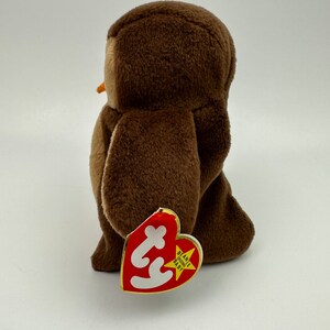 K&ouml;nnte beinhalten: Brauner Pl&uuml;sch-Eulen-Beanie Baby mit einem roten herzf&ouml;rmigen Etikett, auf dem "Beanie Babies Baby" steht.