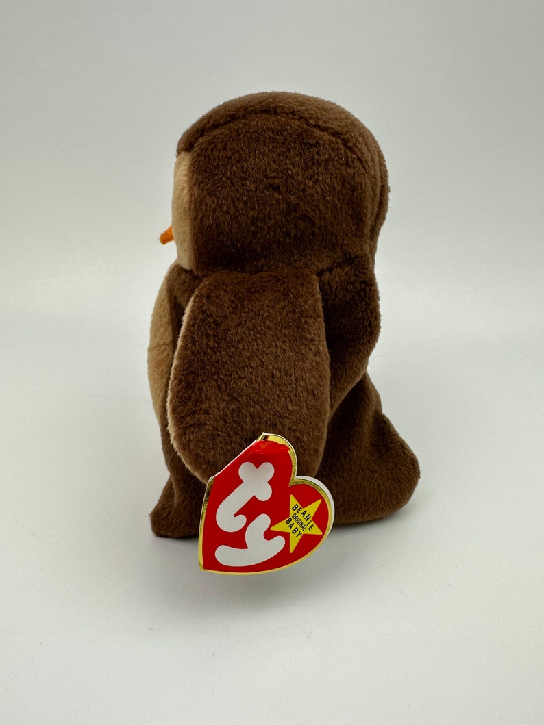 K&ouml;nnte beinhalten: Brauner Pl&uuml;sch-Eulen-Beanie Baby mit einem roten herzf&ouml;rmigen Etikett, auf dem "Beanie Babies Baby" steht.