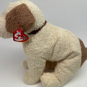 Op de afbeelding: Een wit en bruin pluche hondenspeelgoed met een bruine kraag. Het speelgoed heeft een rood Ty-label.