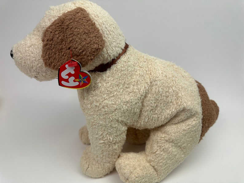 Op de afbeelding: Een wit en bruin pluche hondenspeelgoed met een bruine kraag. Het speelgoed heeft een rood Ty-label.