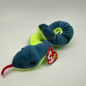 May include: A blue and green snake Beanie Baby with a red tongue and a Ty tag. The tag has a red heart with a white star and the words "Ty Inc." and "Beanie Babies".