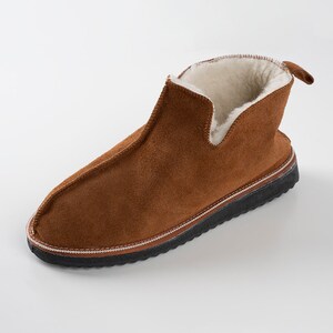 May include: Brown suede slippers with a shearling lining and a black rubber sole.