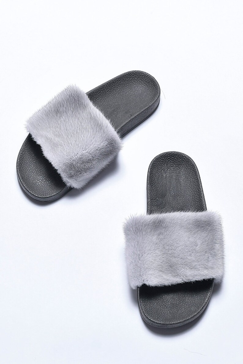 Pu&ograve; includere: Un paio di ciabatte nere con bordo in pelliccia grigia. Le ciabatte hanno un design semplice e sono realizzate in un materiale morbido e confortevole.