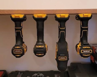 May include: Four yellow and black cordless drills hanging on a wooden shelf. The drills are all the same model and have a black handle and a yellow body. The drills are hanging from hooks on the shelf.