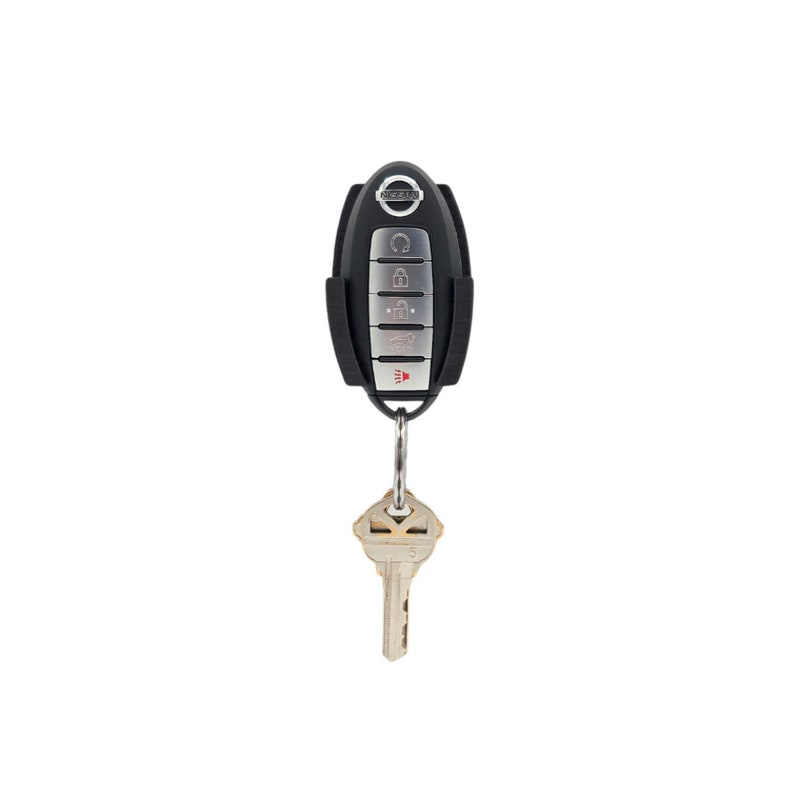 May include: Black key fob with a silver button panel and the Nissan logo. The key fob is attached to a silver key ring with a house key.