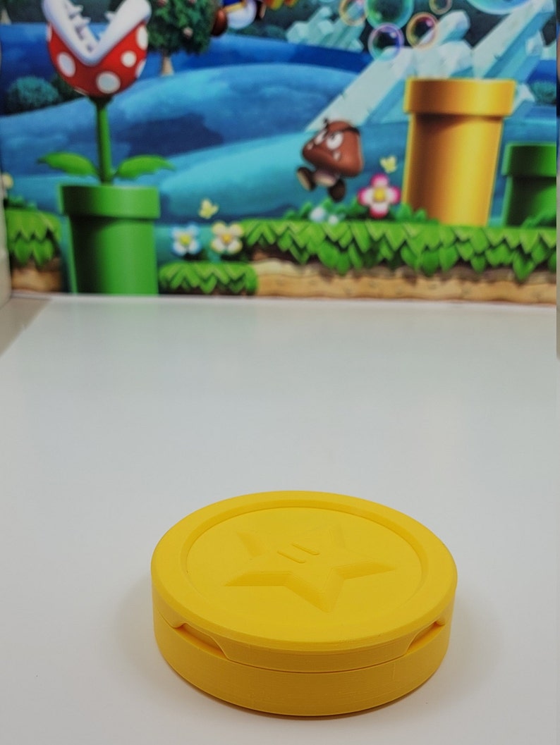 May include: A yellow plastic coin with a star design on the top. The coin is a collectible item for video game fans.