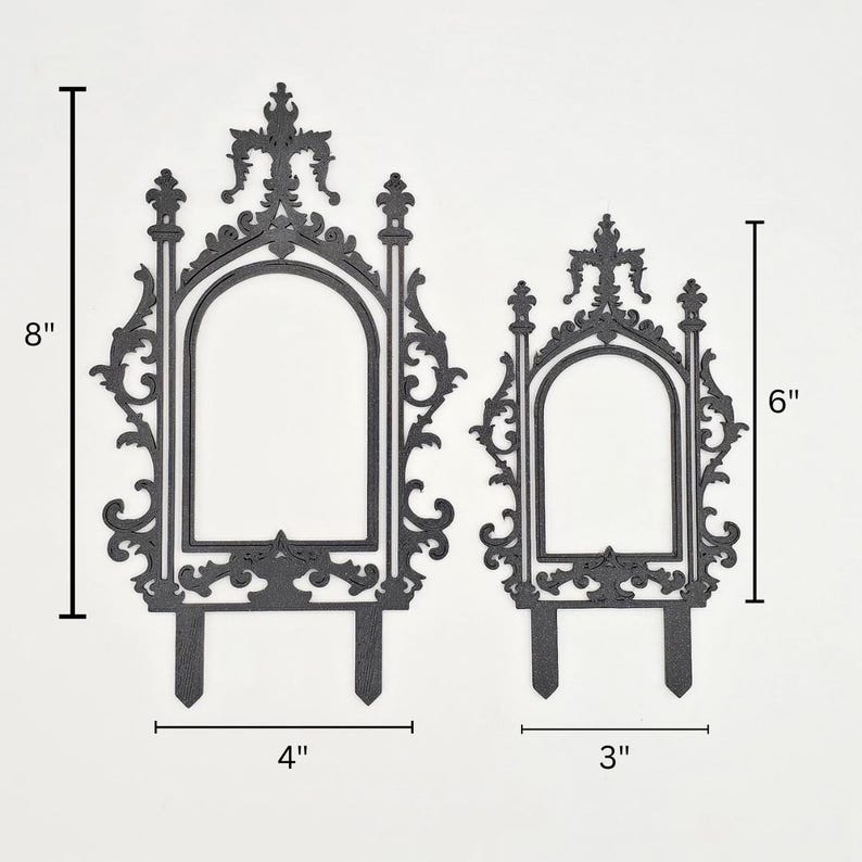 May include: Two black decorative garden stakes. The larger stake is 20 cm tall and 10 cm wide, while the smaller is 15 cm tall and 8 cm wide. Both have an arched window design with ornate detailing and a stake at the bottom.