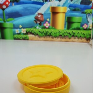 May include: A yellow, round, two-piece container with a star design on the lid. The container is made of plastic and is about 3 inches in diameter.